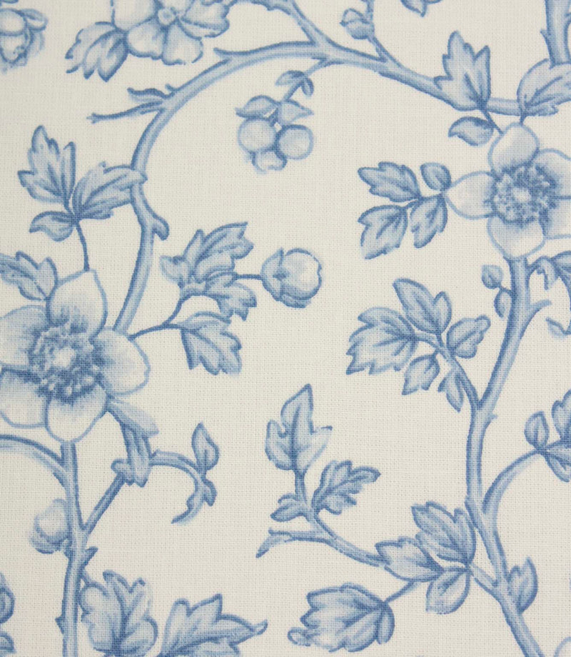 Close-up of blue botanical fabric showing intricate floral vines and fine illustrated detailing on a light neutral base.