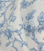 Close-up of folded floral fabric showing the smooth texture and elegant blue vine pattern.