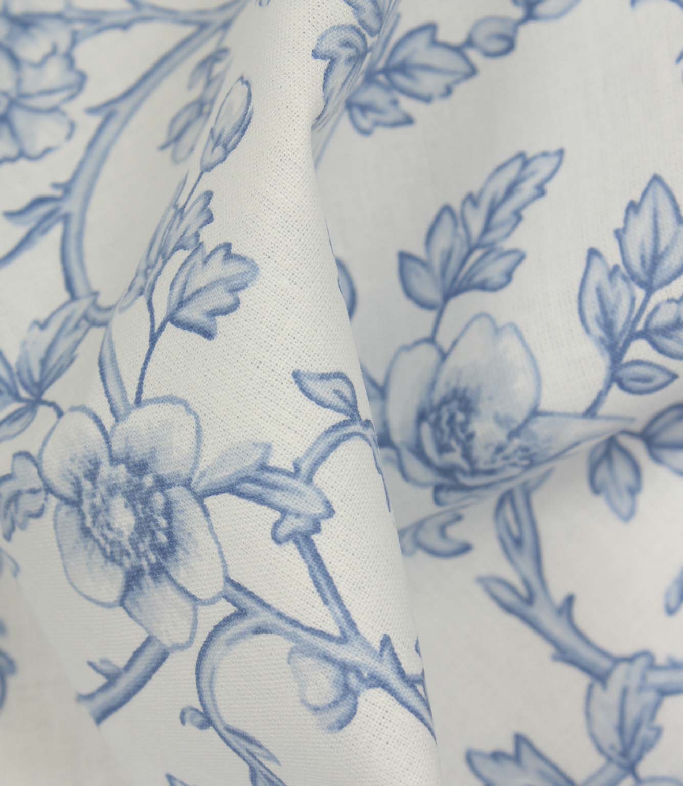 Close-up of folded floral fabric showing the smooth texture and elegant blue vine pattern.