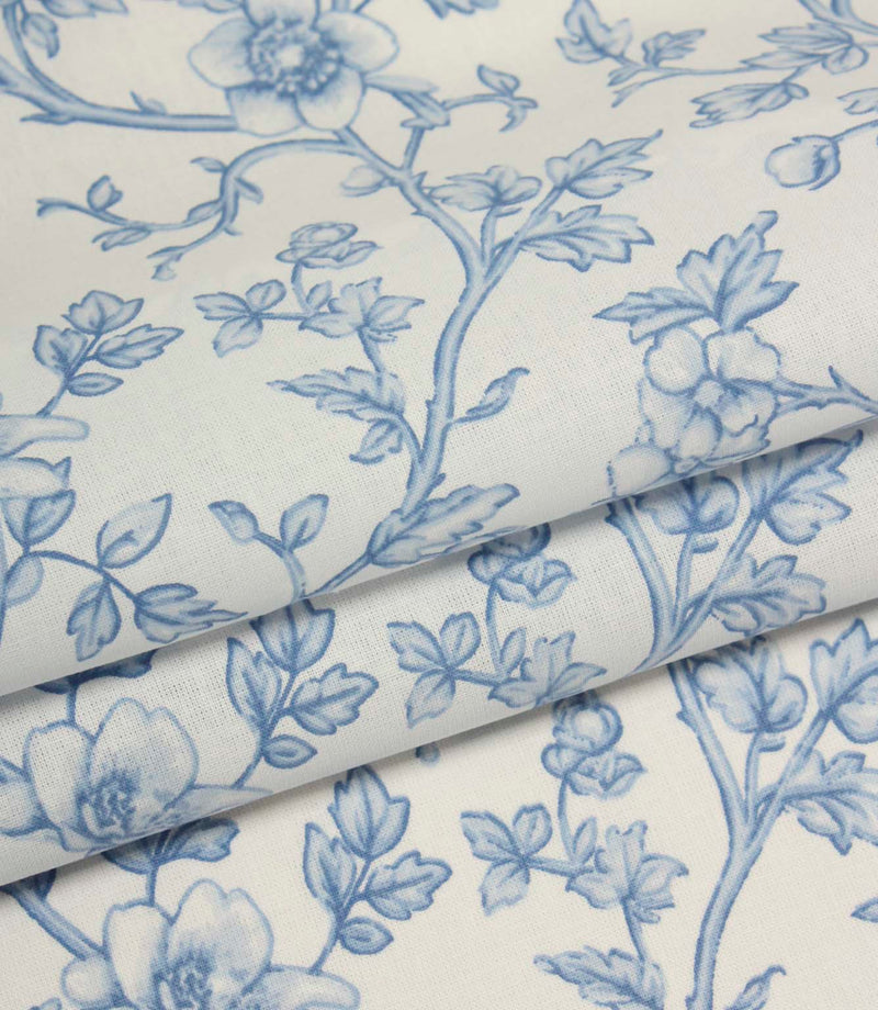 Folded blue botanical print fabric featuring delicate floral trails and soft tonal shading on an ivory background.