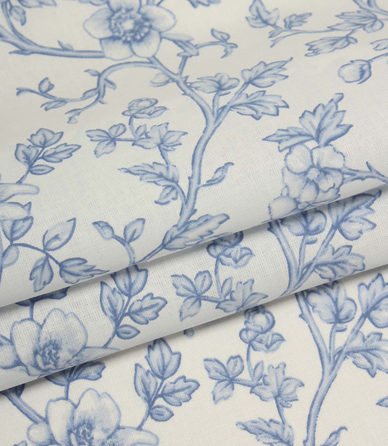 Folded blue botanical print fabric featuring delicate floral trails and soft tonal shading on an ivory background.