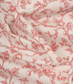Softly draped ivory fabric with a flowing red floral vine pattern, showing the lightweight texture and graceful movement of the material.