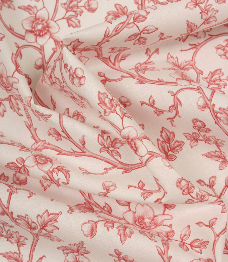 Softly draped ivory fabric with a flowing red floral vine pattern, showing the lightweight texture and graceful movement of the material.