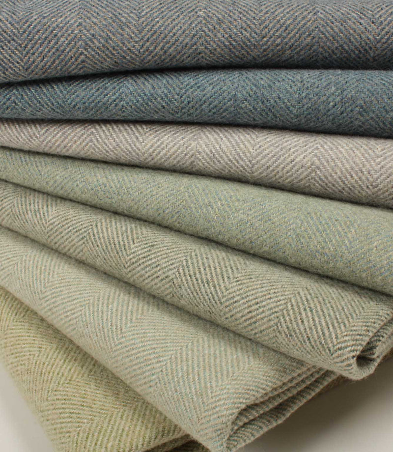 Stack of folded herringbone fabric in various shades of green and blue.