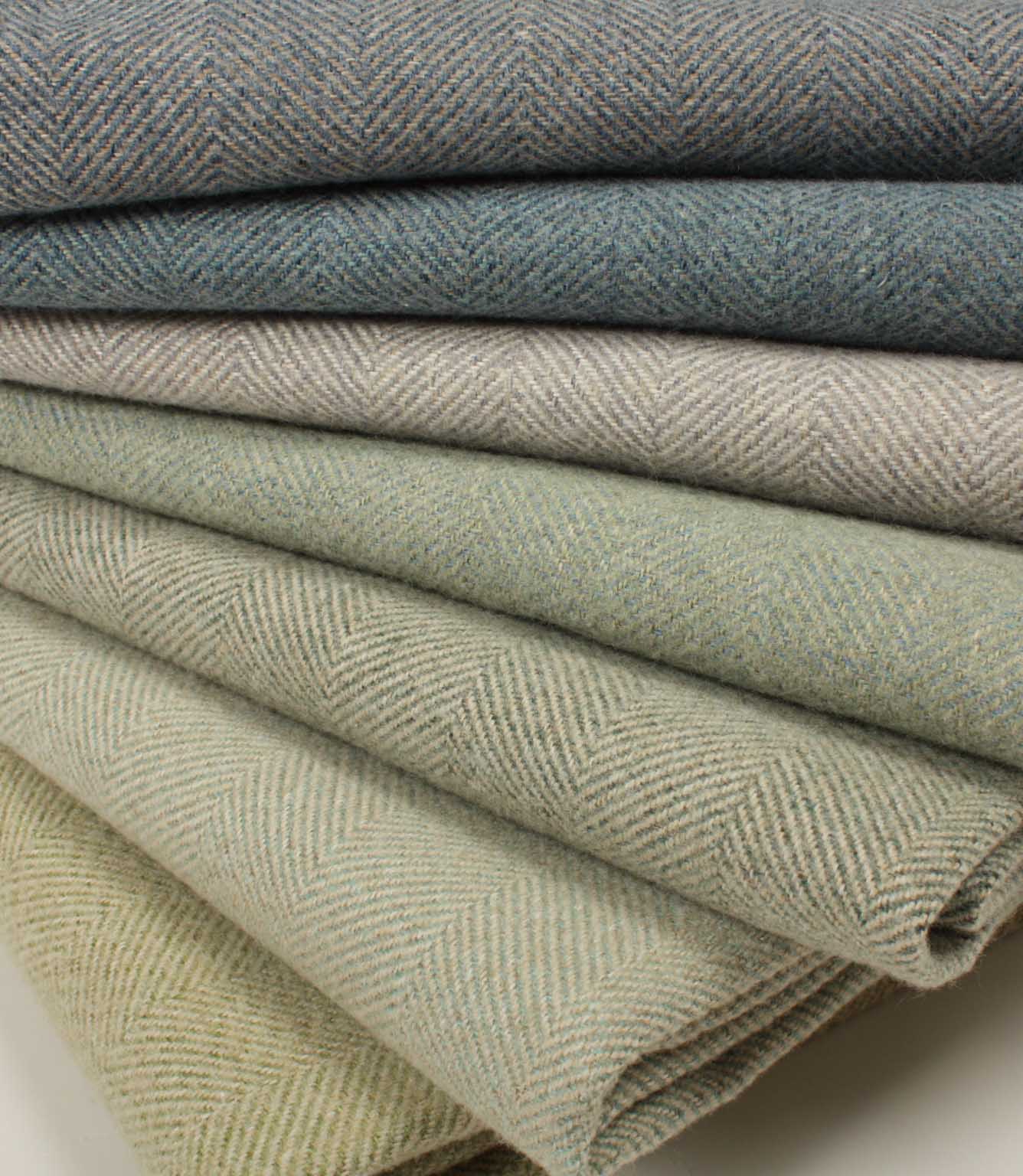 Stack of folded herringbone fabric in various shades of green and blue.