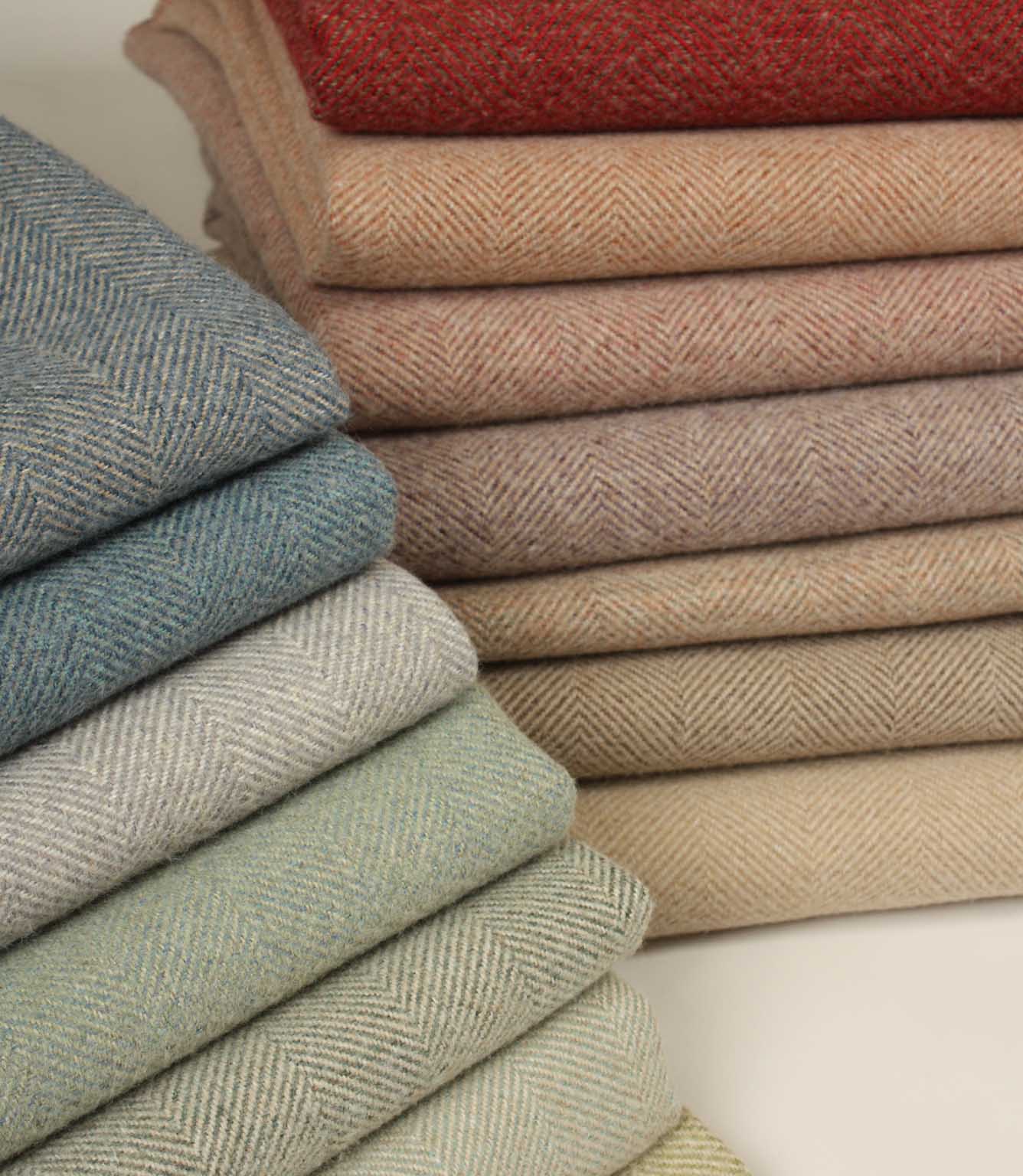 Stack of folded herringbone fabric swatches in various colours on a neutral background