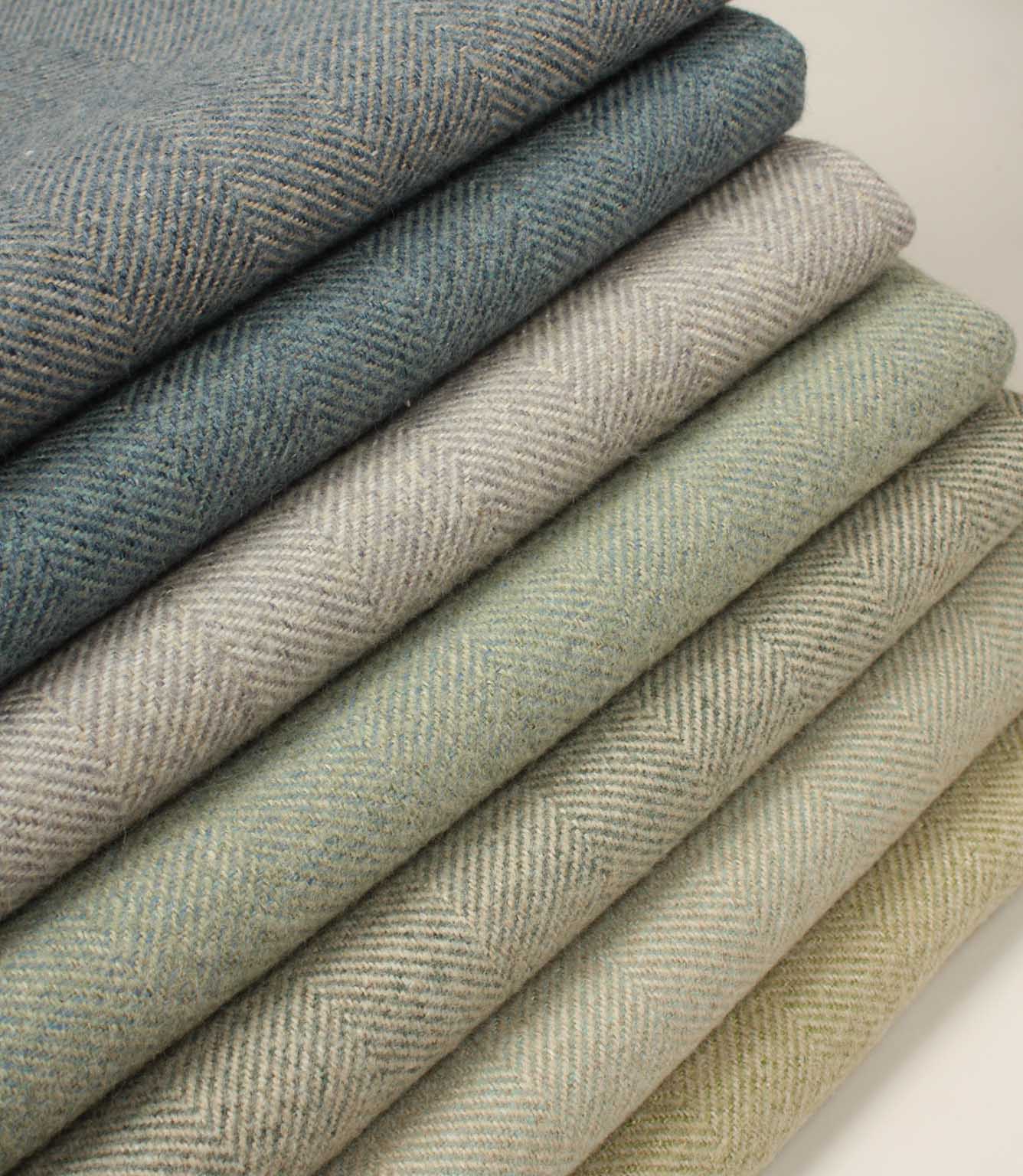 Stack of folded herringbone fabric swatches in various shades of green and blue.