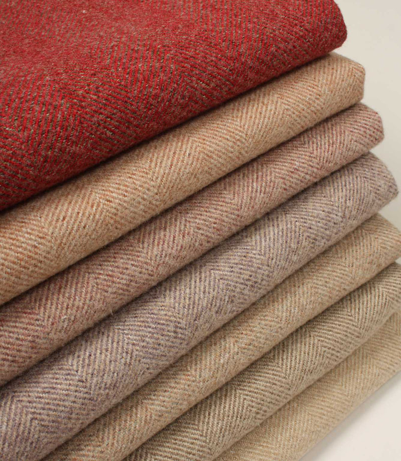 Stack of folded herringbone fabric swatches in red and beige tones on a neutral background