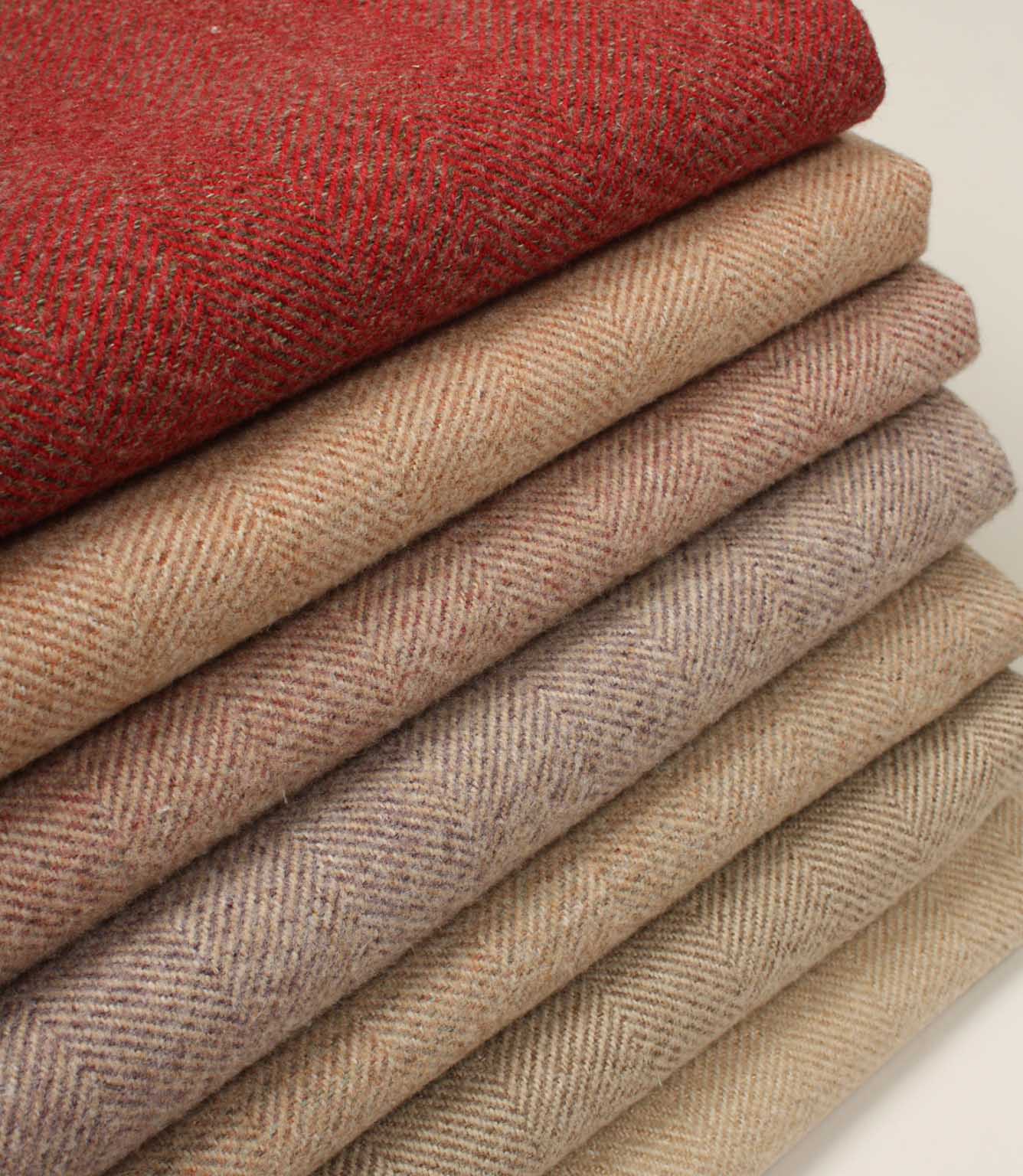 Stack of folded herringbone fabric swatches in red and beige tones on a neutral background