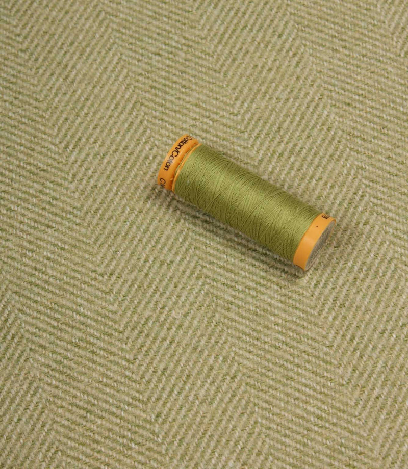 Green spool of thread on a textured fabric background