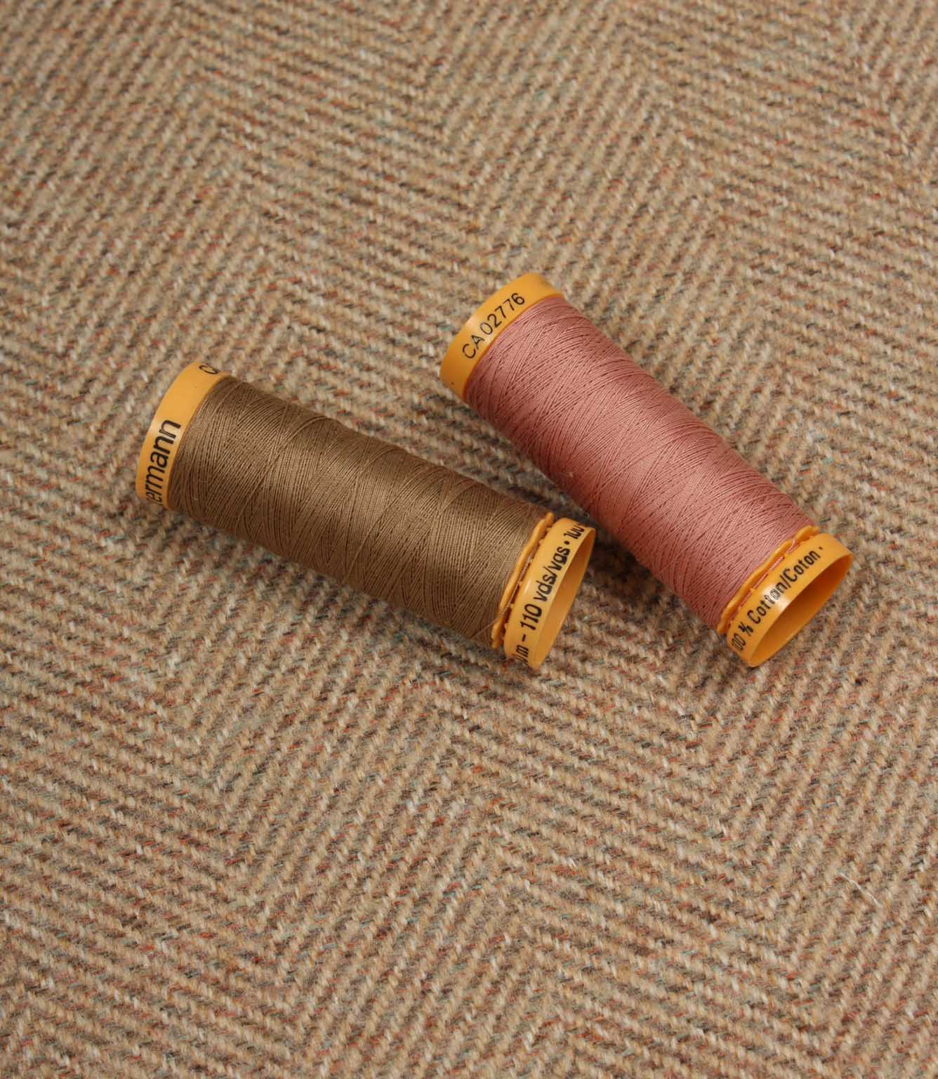 Two spools of thread on a textured fabric background