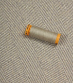 Spool of grey thread on a textured fabric background