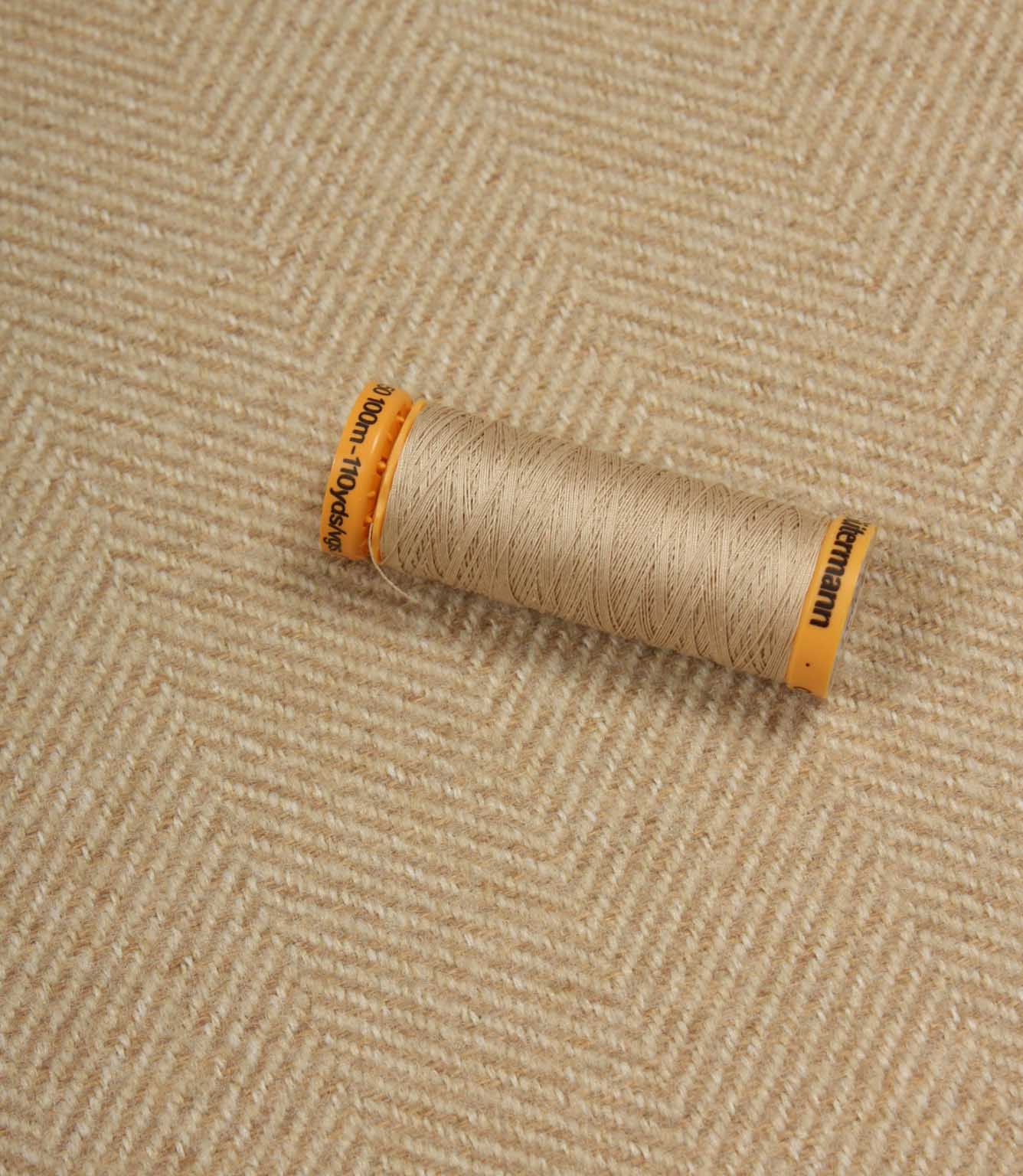 Spool of thread on a textured beige fabric background