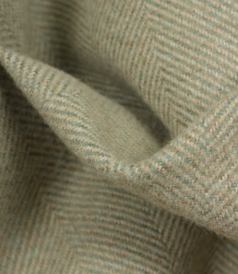 Close-up of a textured fabric with a herringbone pattern in green and beige.