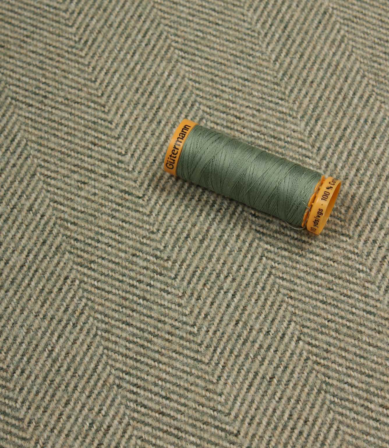 Green spool of thread on a textured fabric background