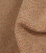 Close-up of herringbone patterned fabric in terracotta tones.