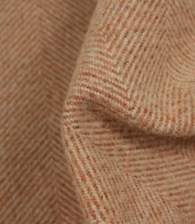 Close-up of herringbone patterned fabric in terracotta tones.