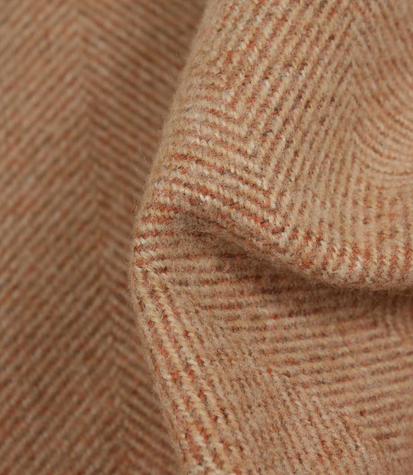 Close-up of herringbone patterned fabric in terracotta tones.