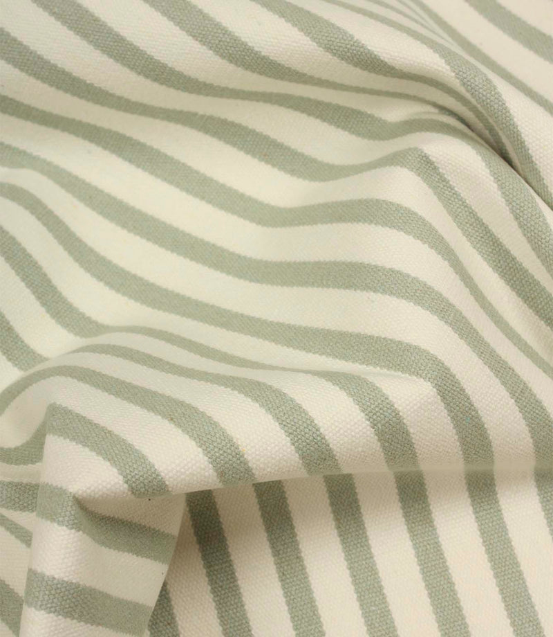 Draped Fernley Stripe woven upholstery fabric featuring soft sage green stripes on ivory, demonstrating the fabric’s natural movement and texture.