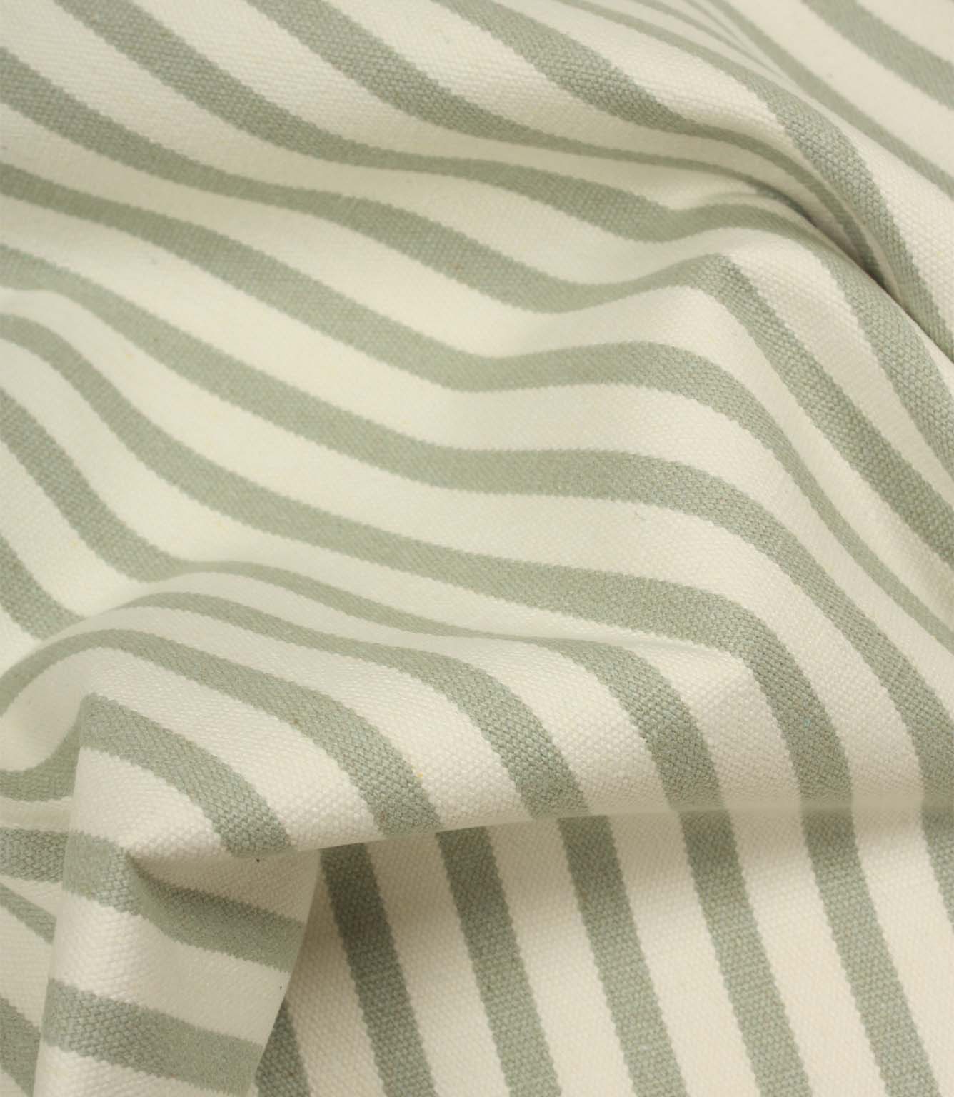 Draped Fernley Stripe woven upholstery fabric featuring soft sage green stripes on ivory, demonstrating the fabric’s natural movement and texture.