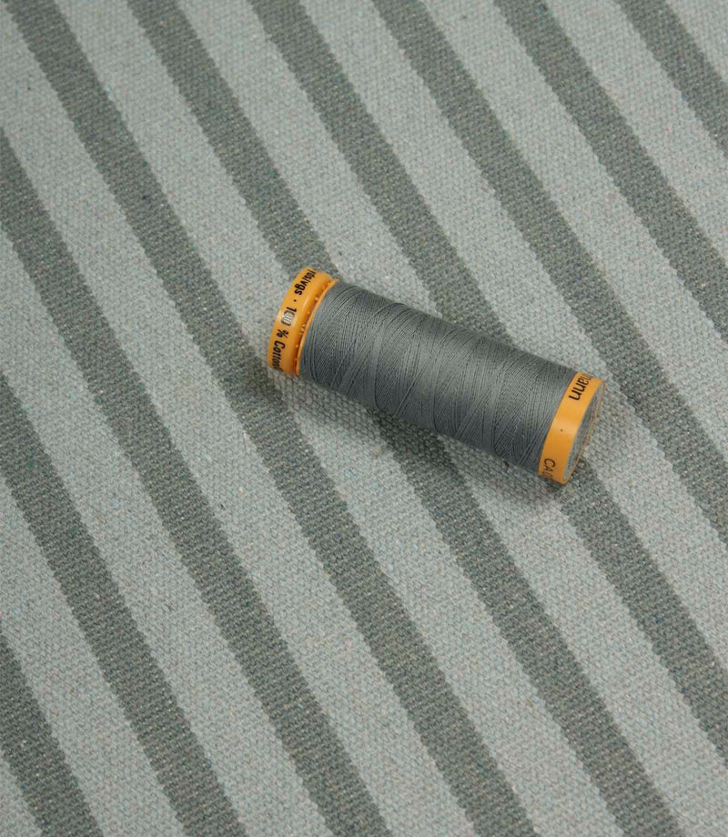 Fernley Stripe steel blue stripe upholstery fabric displayed with matching thread, showcasing colour coordination and woven texture.