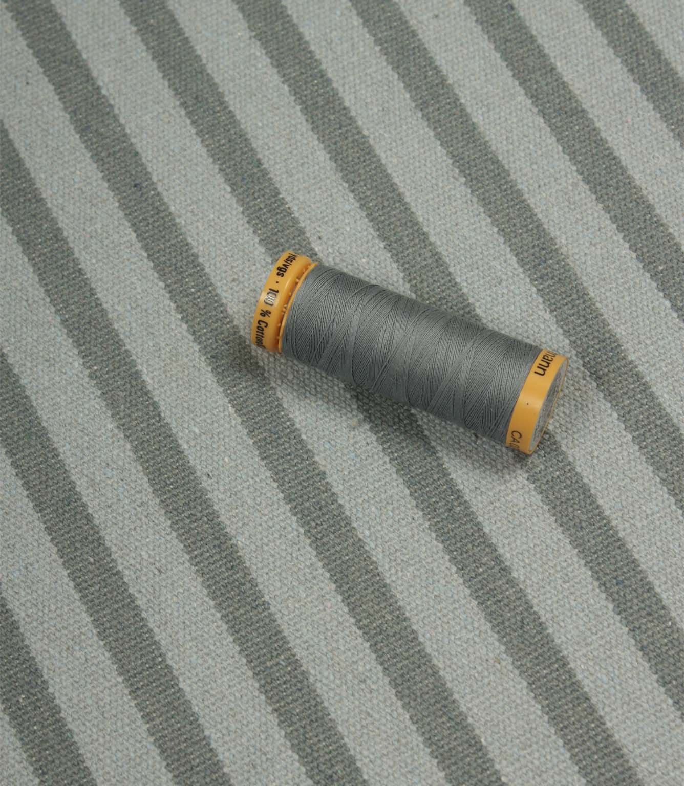 Fernley Stripe steel blue stripe upholstery fabric displayed with matching thread, showcasing colour coordination and woven texture.