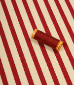 Fernley Stripe wine red stripe upholstery fabric displayed with matching thread, highlighting colour coordination and woven texture.