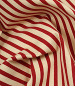 Draped Fernley Stripe woven upholstery fabric with wine red stripes on an ivory background, showcasing the fabric's texture and elegant flow.