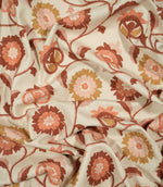 Foxmere Burnt Sienna embroidered fabric loosely draped to show its texture and handle, with a repeating botanical design of winding stems, leaves and decorative flowers across a natural cream woven background.