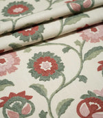 Foxmere Chintz fabric arranged in gentle folds, displaying its repeating embroidered botanical design of curving green vines, two-tone leaves and stylised flowers and buds in soft pink, muted red and sage green.