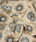 Draped embroidered fabric featuring elegant floral motifs in cornflower blue, slate grey and beige with a soft, flowing finish.