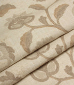 Folded natural embroidered fabric featuring intricate floral motifs and trailing vines on a soft woven base cloth.