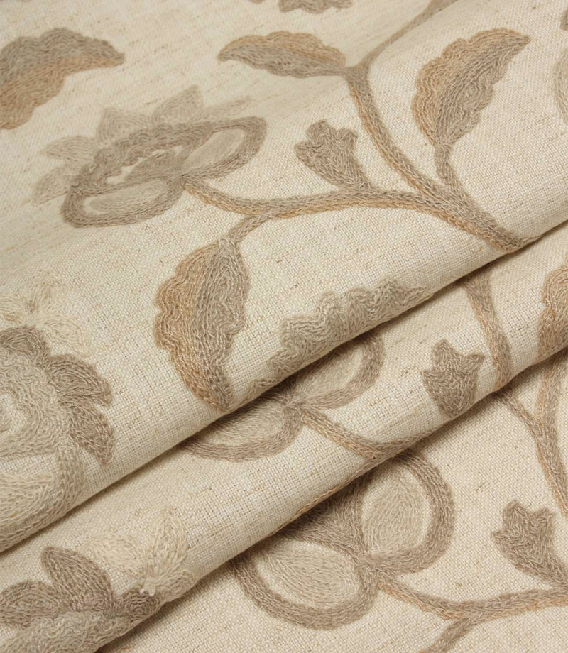 Folded natural embroidered fabric featuring intricate floral motifs and trailing vines on a soft woven base cloth.