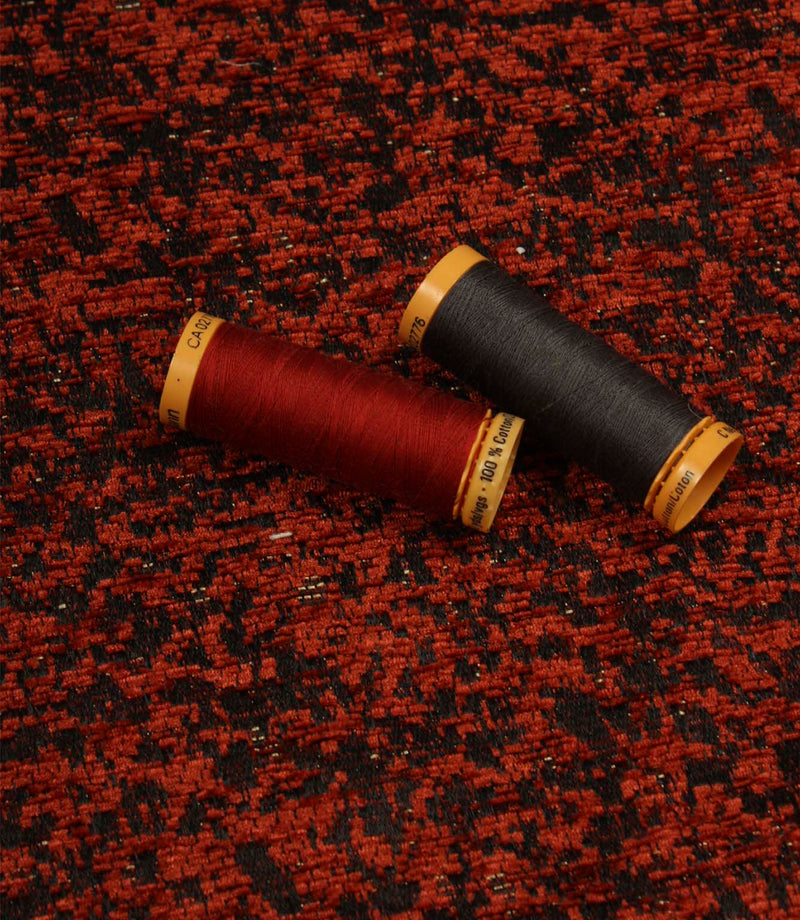 Galaxy woven fabric displayed with matching thread spools, highlighting the contemporary texture in copper and black shades.