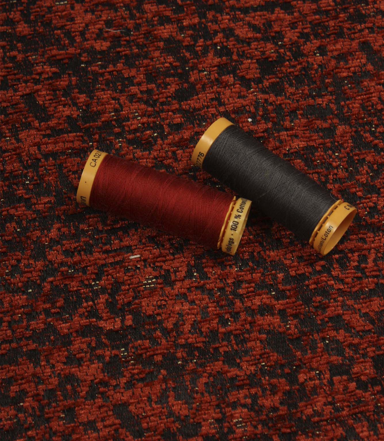 Galaxy woven fabric displayed with matching thread spools, highlighting the contemporary texture in copper and black shades.