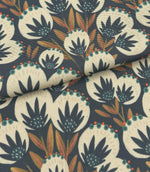 Folded Ember Crest outdoor fabric featuring cream botanical motifs with teal, coral, and ochre detailing on a deep navy background.