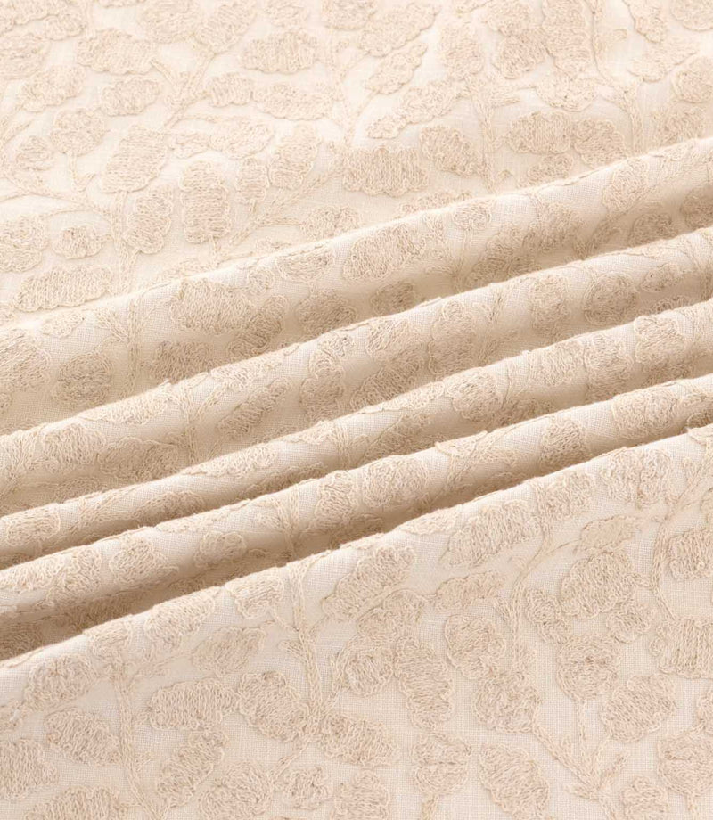 Gardiner Oyster fabric draped in gentle folds, highlighting the subtle beige botanical embroidery, raised leaf detailing and soft ivory background.