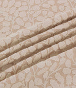 Gardiner Shell fabric gathered into gentle folds, showing the raised ivory embroidered botanical pattern against a blush-beige background and its detailed woven texture.