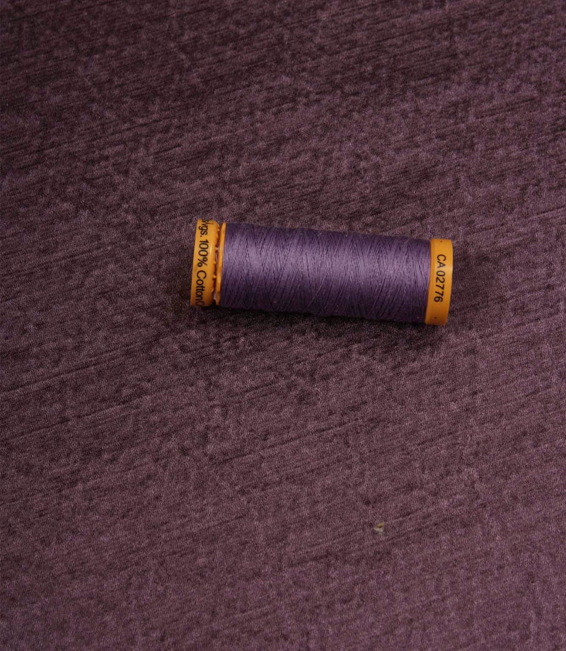 Glaze plum plain fabric with matching thread spool, highlighting its textured appearance and satin-inspired finish.