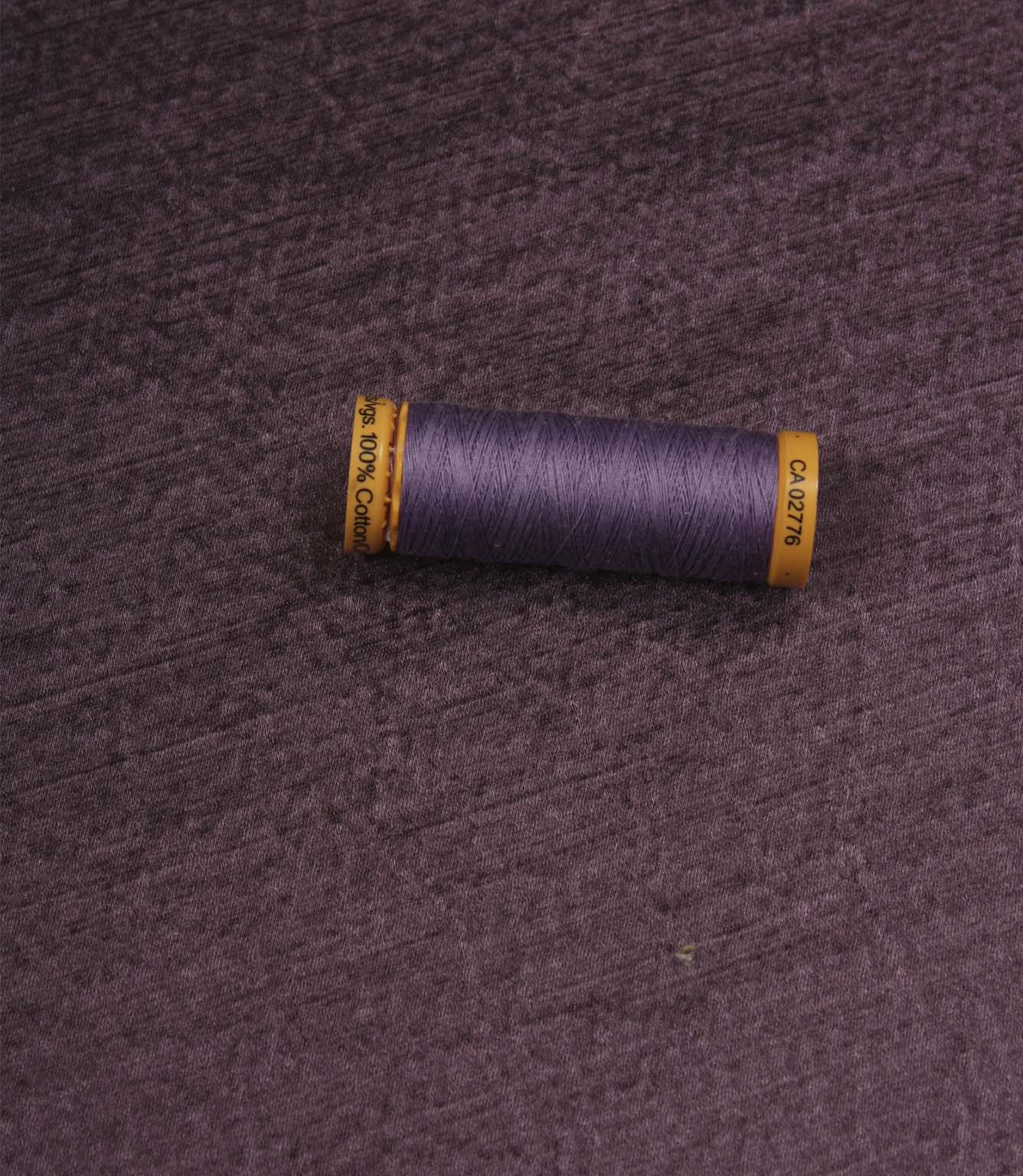 Glaze plum plain fabric with matching thread spool, highlighting its textured appearance and satin-inspired finish.
