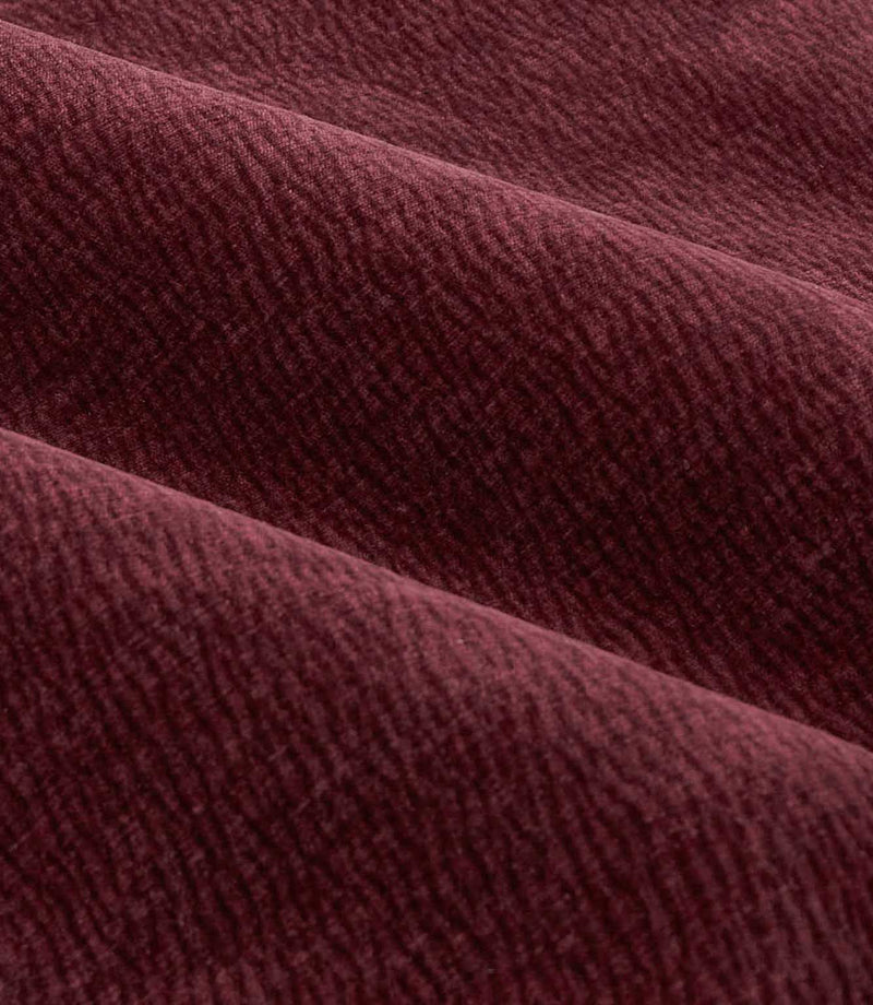 Close-up of folded deep beetroot red Heath washed velvet fabric, showing its plush pile, subtle woven texture and softly shaded finish.