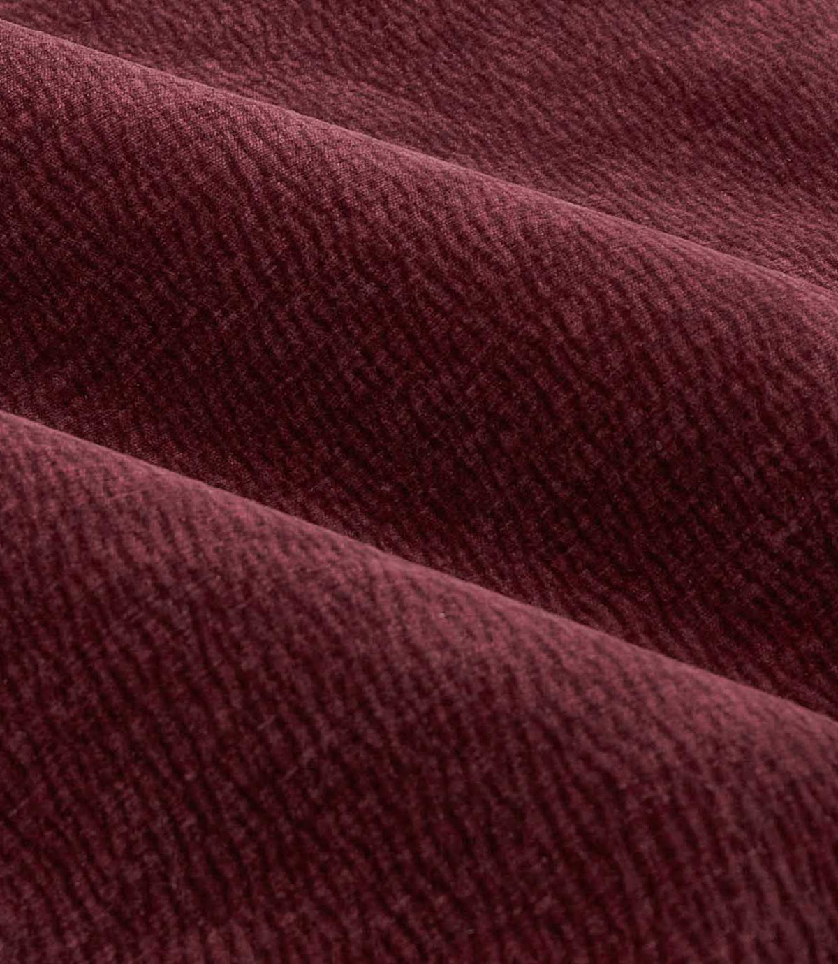 Close-up of folded deep beetroot red Heath washed velvet fabric, showing its plush pile, subtle woven texture and softly shaded finish.