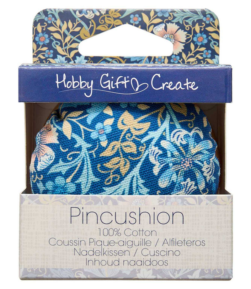 William Morris-inspired floral pincushion in retail packaging, featuring a navy blue, turquoise, cream and gold botanical pattern and natural wooden base.