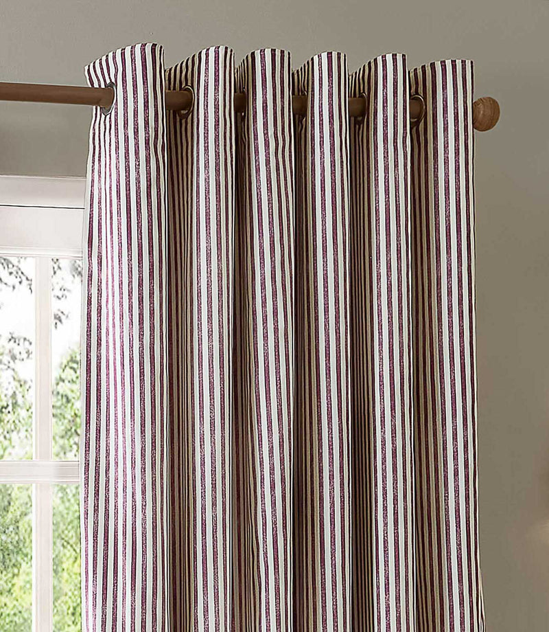 A close-up of striped curtain panels hanging from a wooden rod. The curtains have vertical stripes in brown, beige, and muted red/pink, with grommets on the side.