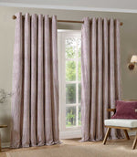 A pair of floor-length striped curtains hanging on a wooden rod over a white window in a styled room with a chair and wall lamp.