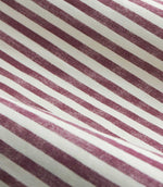 A close-up of striped fabric with alternating dusty burgundy and off-white diagonal stripes.