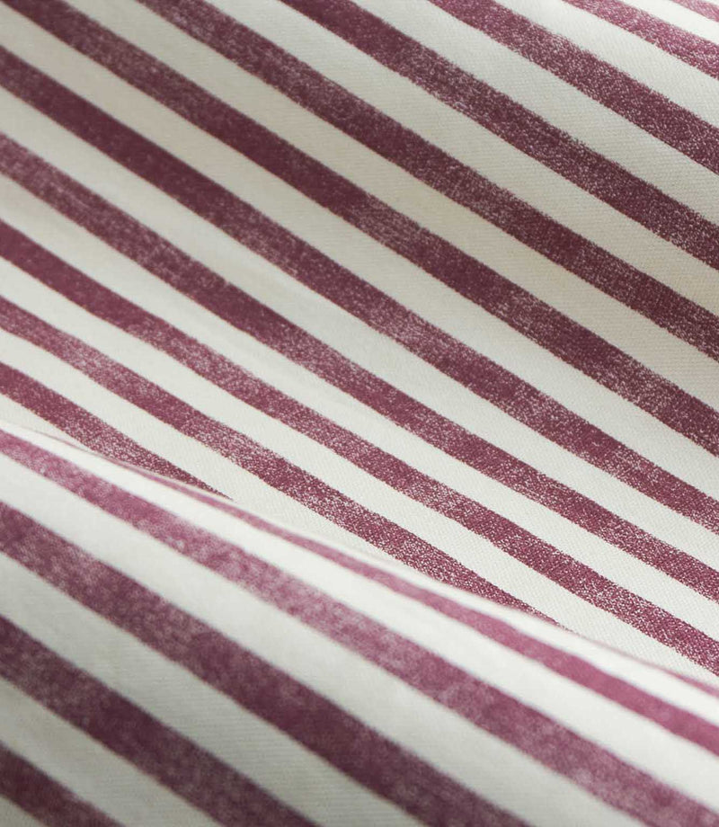 A close-up of striped fabric with alternating dusty burgundy and off-white diagonal stripes.