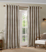 Pair of full-length brown and cream striped eyelet curtains framing a large window, styled in a neutral living room with a wooden armchair and natural textures.
