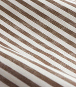 Close-up of brown and cream striped curtain fabric arranged in soft folds, showing the woven texture and slightly irregular printed vertical stripes.
