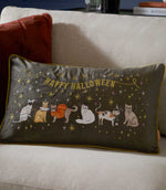 Halloween Pawty charcoal grey velvet cushion styled on a cream sofa, featuring gold Happy Halloween embroidery and multicoloured cats dressed in Halloween costumes.